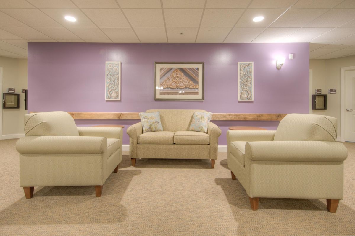 A cozy living room with a cream sofa and armchairs against a purple accent wall.