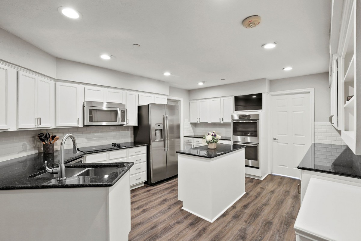 A modern kitchen with white cabinets, stainless steel appliances, and a central island.