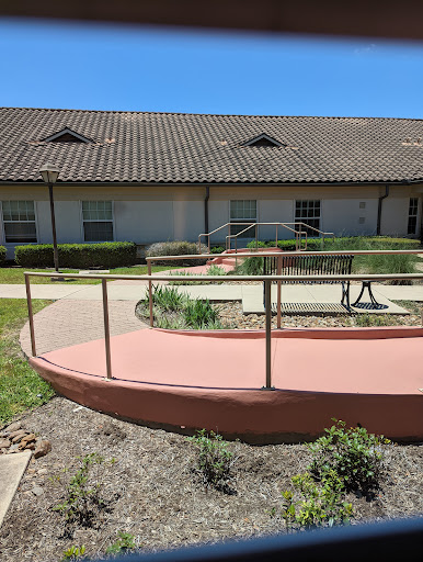A view of a wheelchair-accessible ramp leading to a building with landscaped gardens.