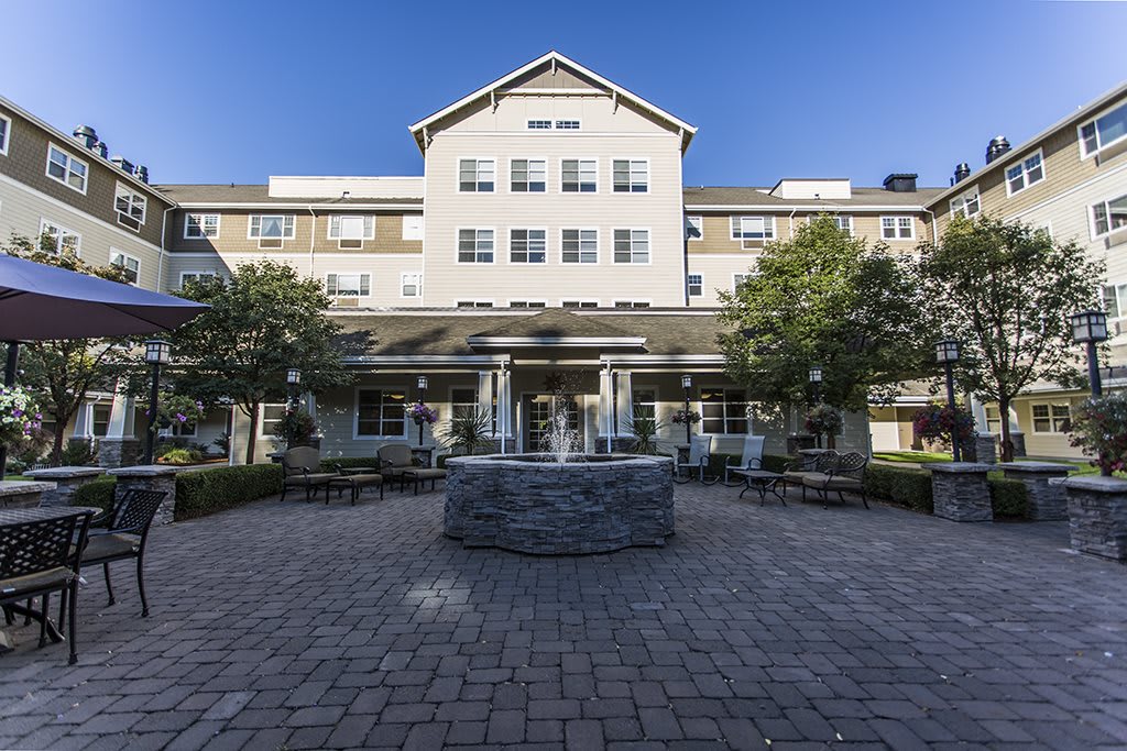 A view of a building with a courtyard and fountain in front.