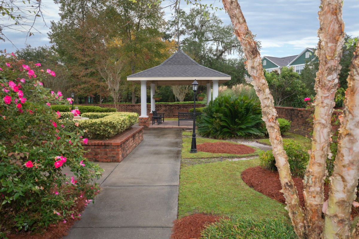 A picturesque garden scene featuring a gazebo, surrounded by a well-maintained pathway and vibrant landscaping.