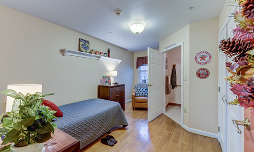 A cozy bedroom with a single bed, wooden flooring, and simple decor.