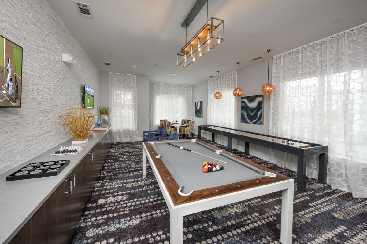 A modern game room featuring a pool table, stylish lighting, and contemporary artwork.