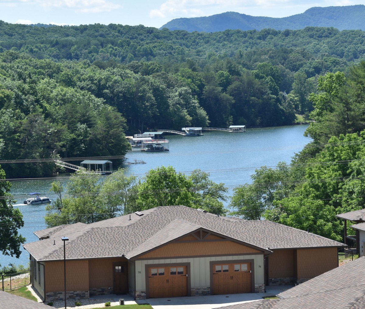 A scenic view of a tranquil lake surrounded by lush green mountains, with houses in the foreground.