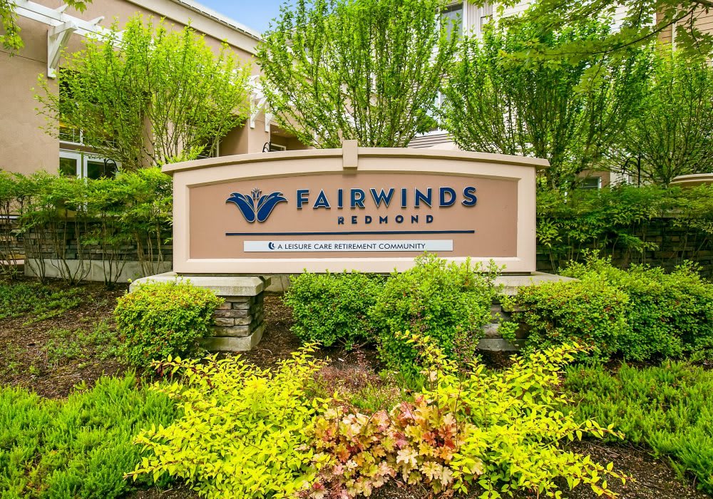 Entrance sign of Fairwinds Apartments surrounded by lush greenery.