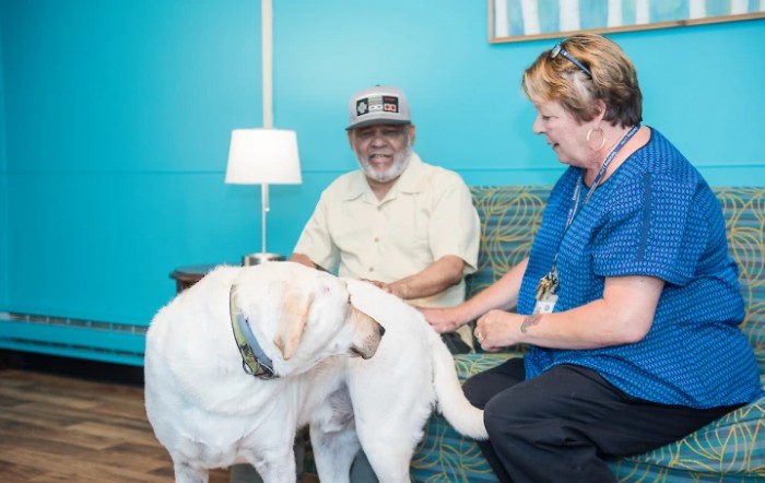 Two people enjoying time with a therapy dog indoors.