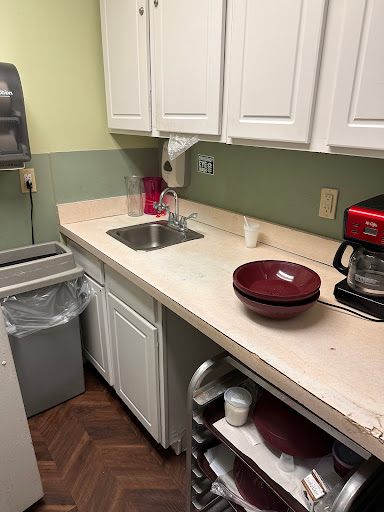 A cozy kitchen setup featuring a countertop with a sink, coffee maker, and bowl.