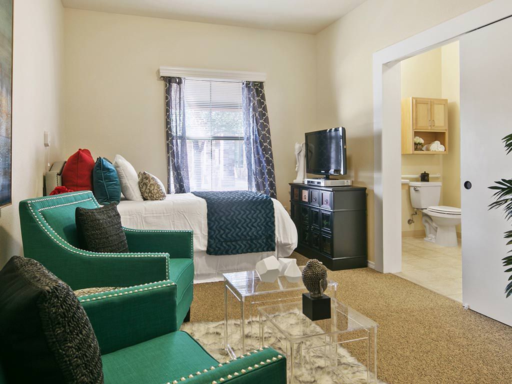 A cozy living space with a bed, seating area, and television.