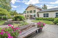 A picturesque garden setting with a wooden bench and colorful flowers in front of a charming house.
