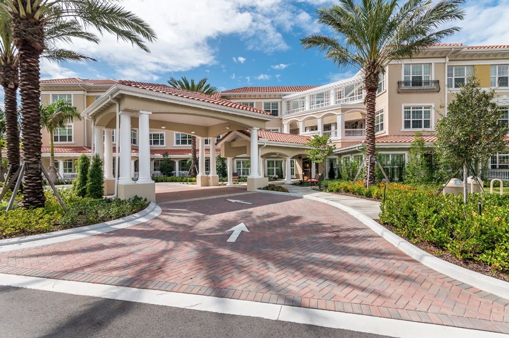 Elegant building entrance with palm trees and a welcoming driveway.