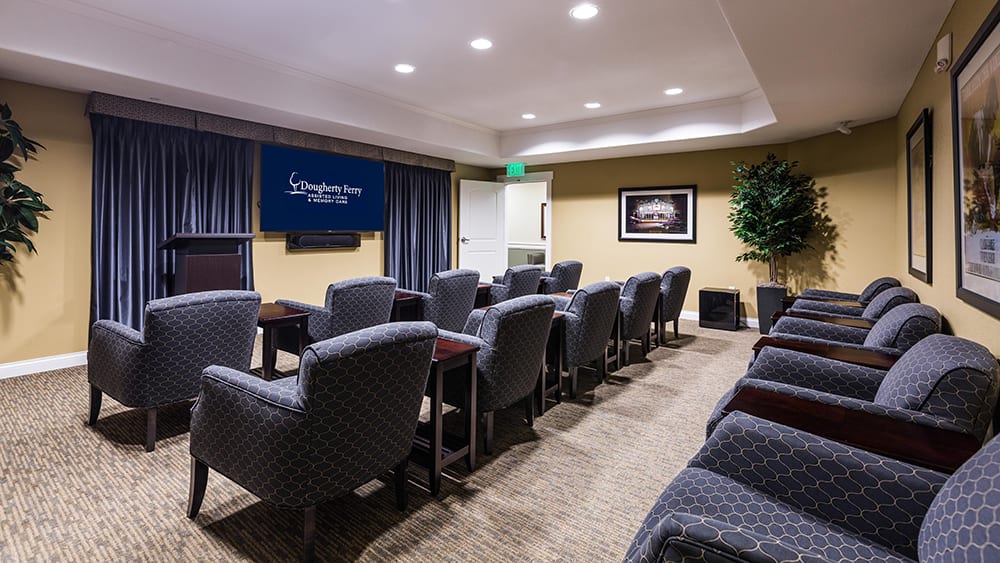 A well-arranged conference room with comfortable seating and a projector screen, suitable for meetings or presentations.