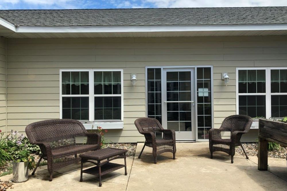 A cozy patio area with wicker furniture in front of a building with large windows and doors.