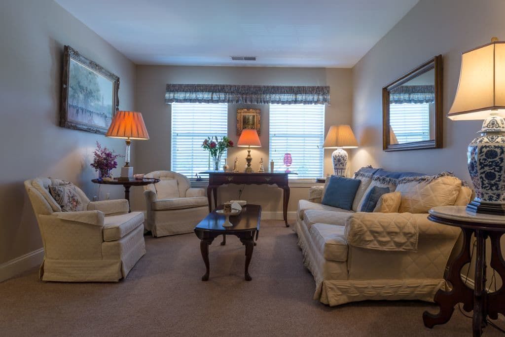 A cozy living room with comfortable sofas, armchairs, and various lamps creating a warm ambiance.