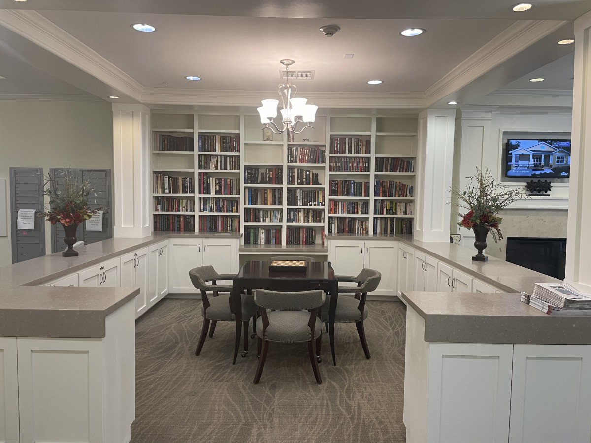 A cozy library space with white bookshelves and a central table with chairs.