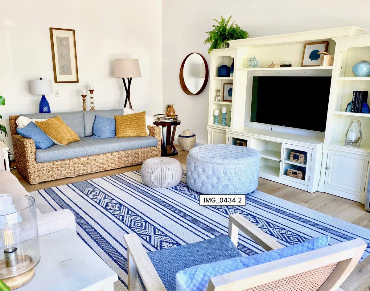 A cozy living room with a blue and white color scheme, featuring a comfortable sofa, decorative cushions, and a stylish rug.