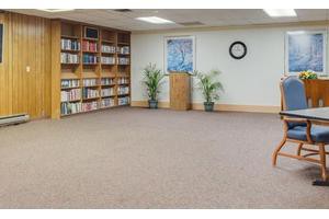A quiet room with a bookshelf, podium, and plants, ideal for meetings or reading.