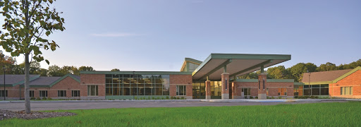 A modern educational or community building set against a clear sky and lush green grass.