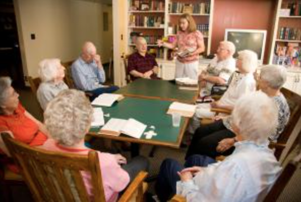 A group of seniors engaging in a book club discussion in a cozy library setting.