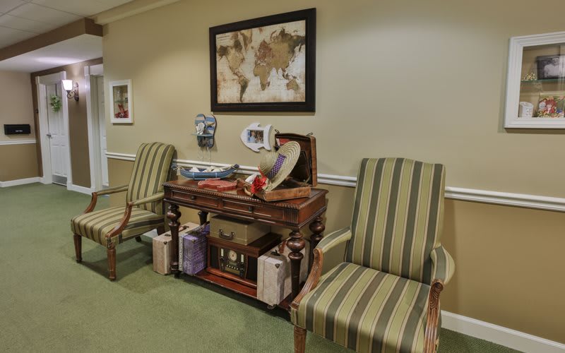 A cozy interior featuring two striped chairs and a decorative table adorned with various items and artwork on the wall.