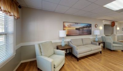 A cozy waiting room with comfortable seating, lamps, and a scenic artwork on the wall.
