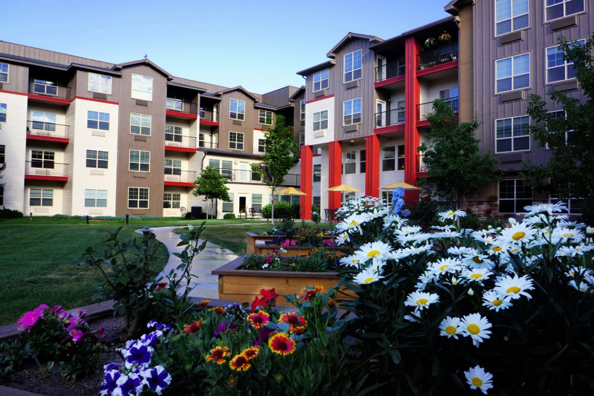 A beautifully landscaped apartment complex with vibrant flower gardens.