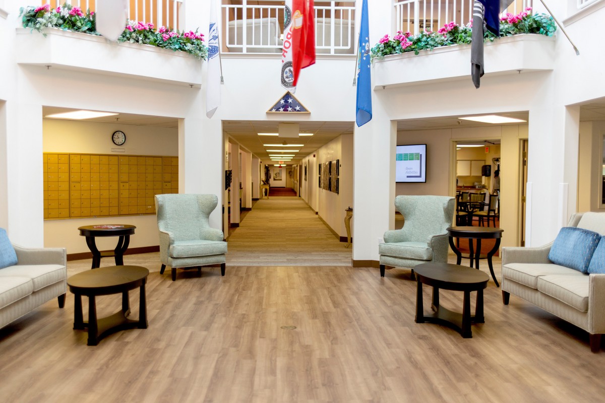 A decorated lobby area featuring chairs, a hallway, and various flags displayed above.