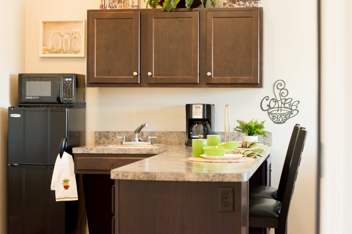A modern kitchen with a marble countertop, wooden cabinets, and a coffee maker.