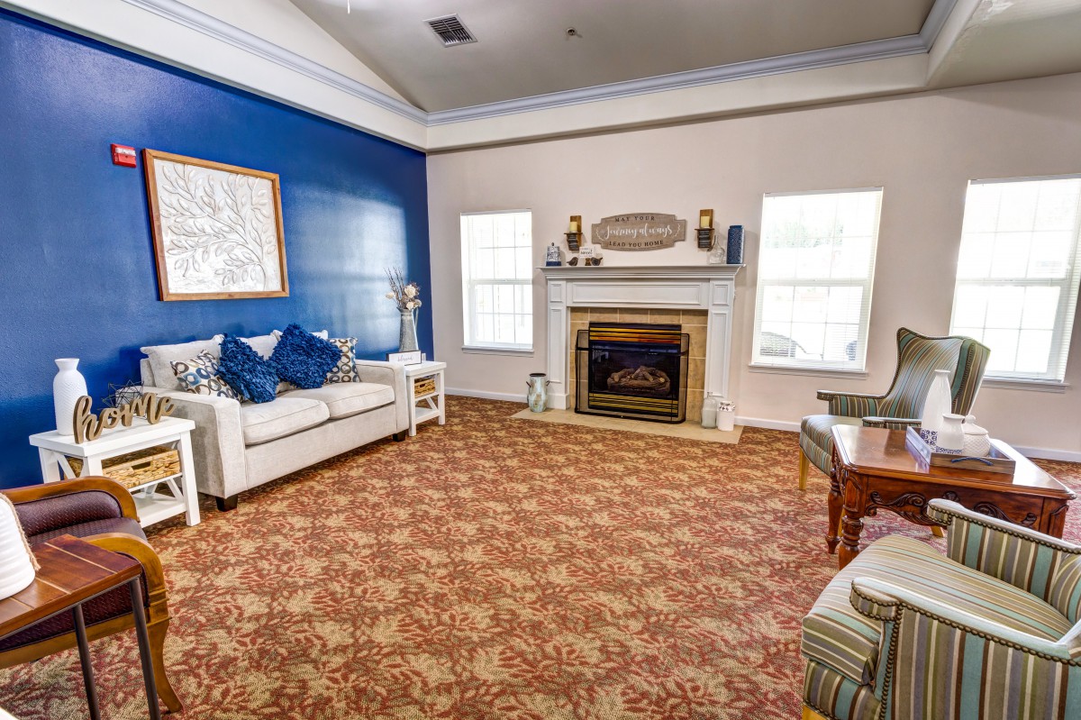 A cozy living room with a blue accent wall, featuring a sofa and fireplace.