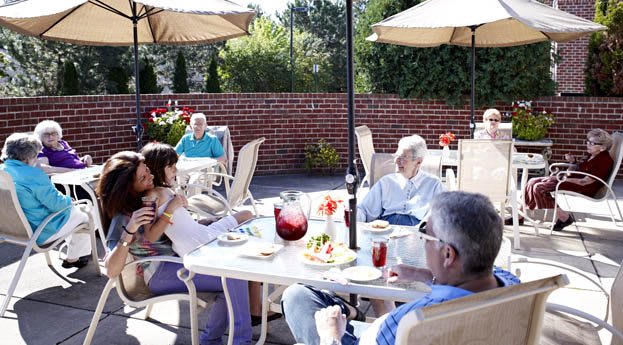 A group of people enjoying a relaxing time on a patio with food and drinks.