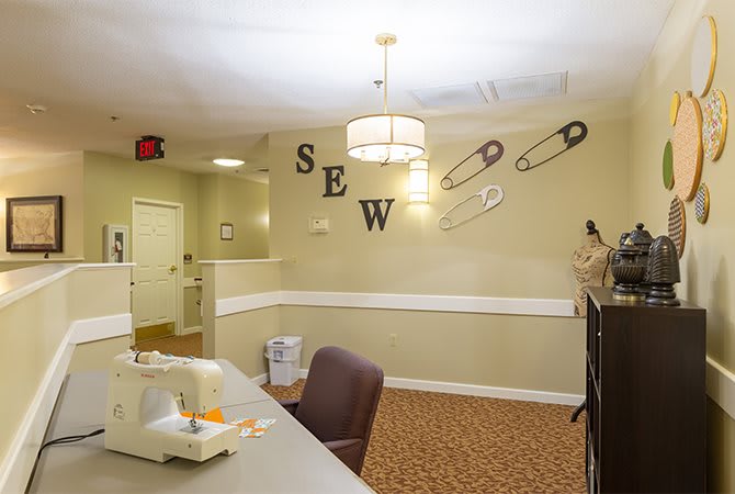 A cozy sewing room featuring a sewing machine and decorative elements including safety pins and the word 'SEW' on the wall.