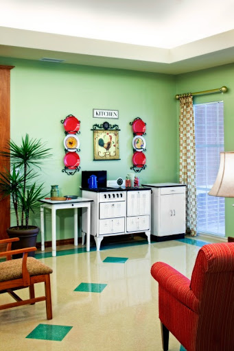 A stylish vintage-inspired living room showcasing green walls, retro furniture, and decorative artwork.