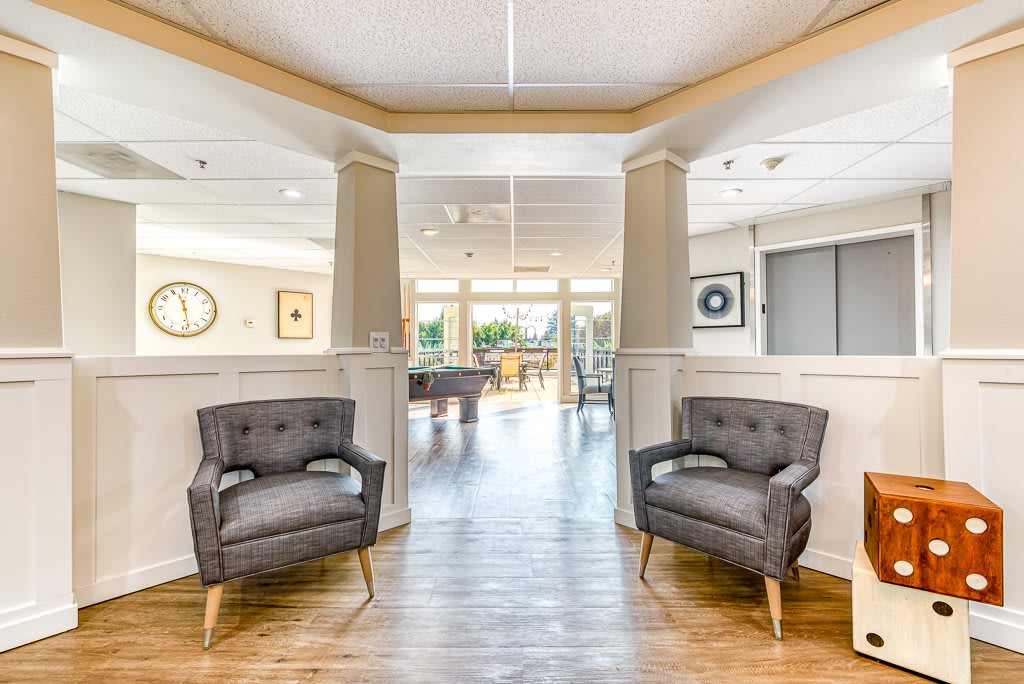 A well-lit, modern living room featuring stylish armchairs and a glimpse of a dining area in the background.