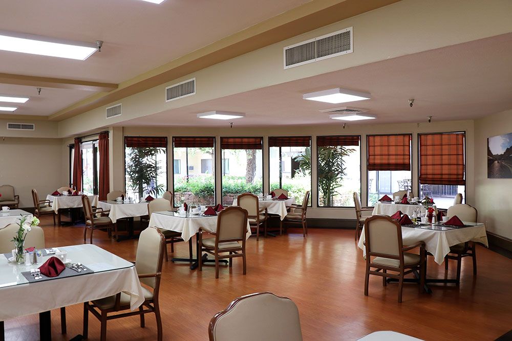 A spacious dining area with neatly arranged tables and chairs, featuring large windows.