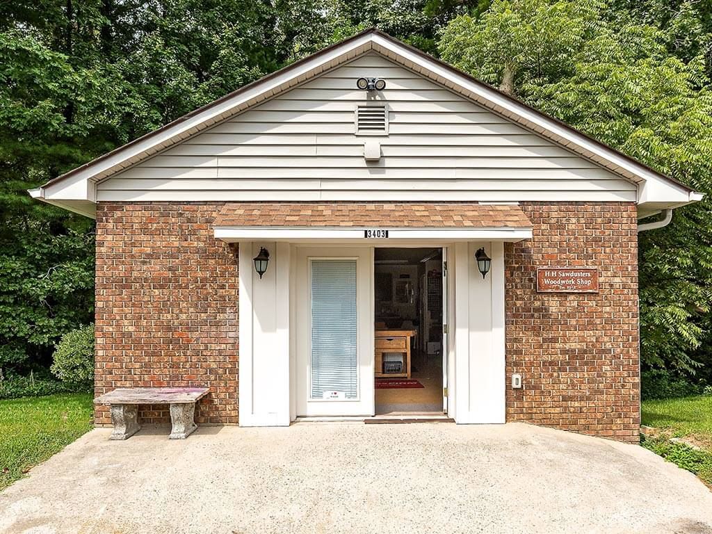 Front view of a brick building with an open entrance and a small bench to the side.