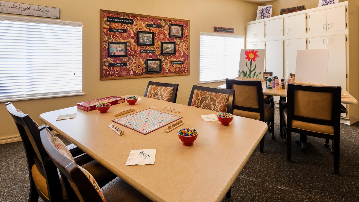 A cozy meeting room with a Scrabble game set up on a table, surrounded by chairs and decorated with colorful artwork.
