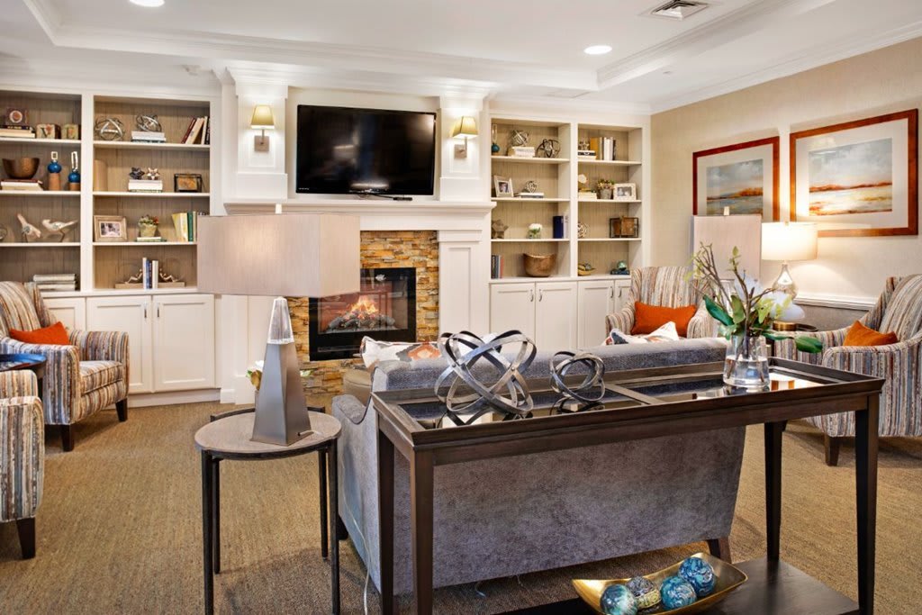 A cozy living room featuring a fireplace, built-in bookshelves, a comfortable sofa, and a flat-screen TV.