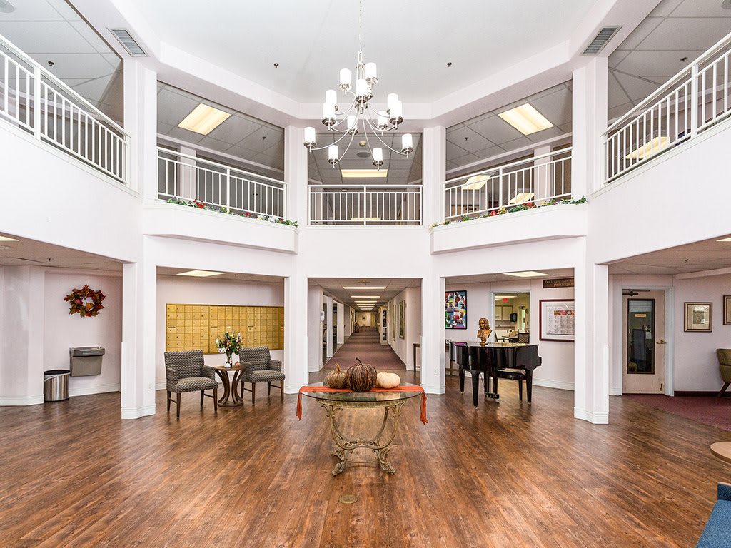 Spacious and elegant lobby with a chandelier, wooden flooring, and a grand piano.