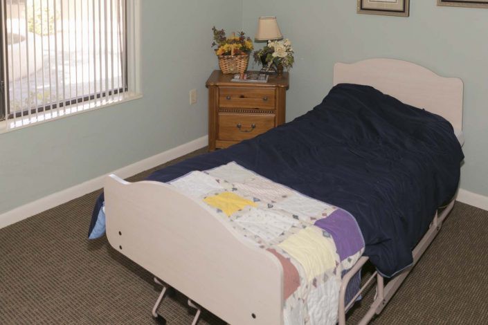 A bedroom with a hospital bed and a nightstand beside it.