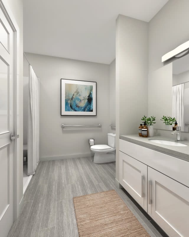 A modern bathroom featuring a sleek design with a shower, toilet, and vanity set, accented by artwork and greenery.