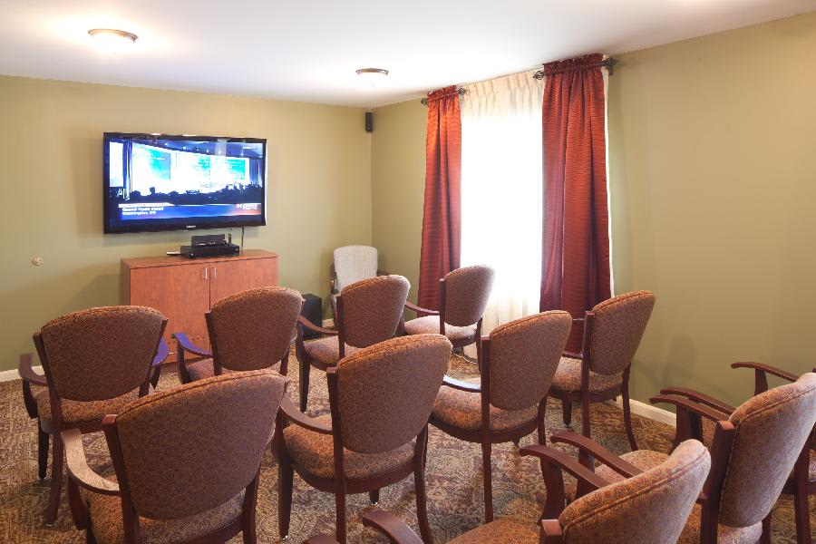 A small conference room with rows of chairs facing a television screen.