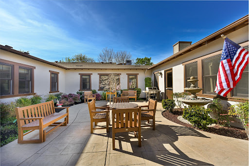 A spacious outdoor patio featuring wooden furniture under a clear blue sky.