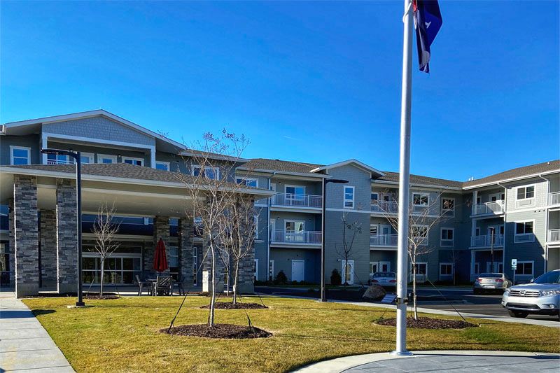 A modern building with a flagpole standing on a well-maintained lawn under a clear blue sky.