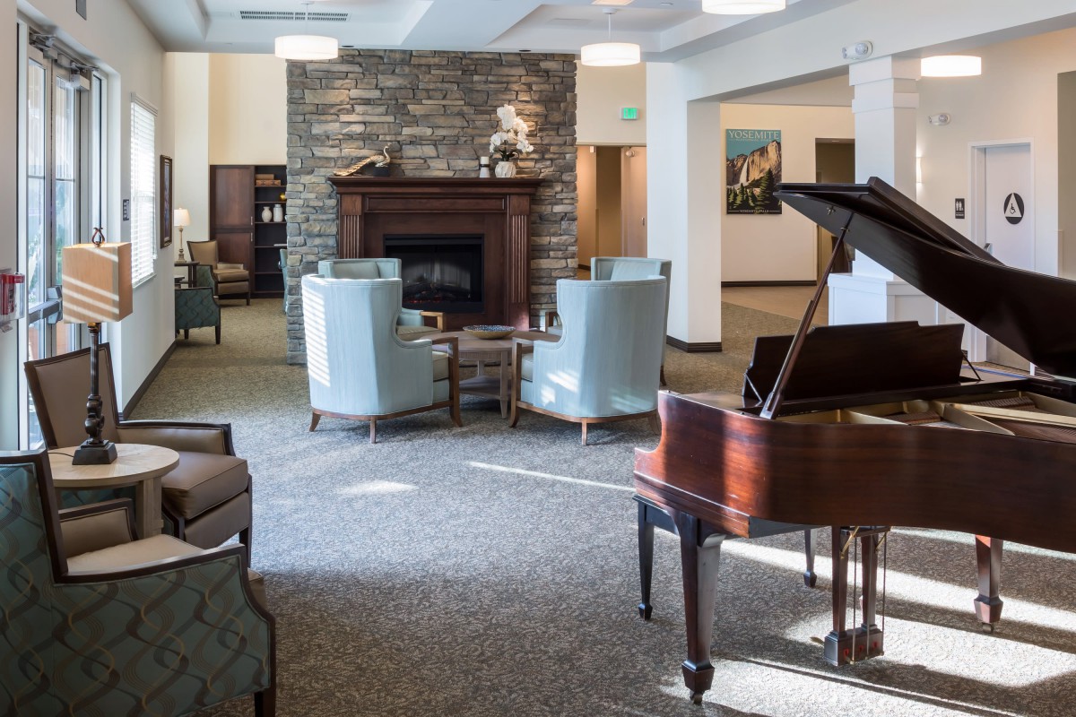 A cozy living room featuring a piano and a fireplace surrounded by comfortable chairs.