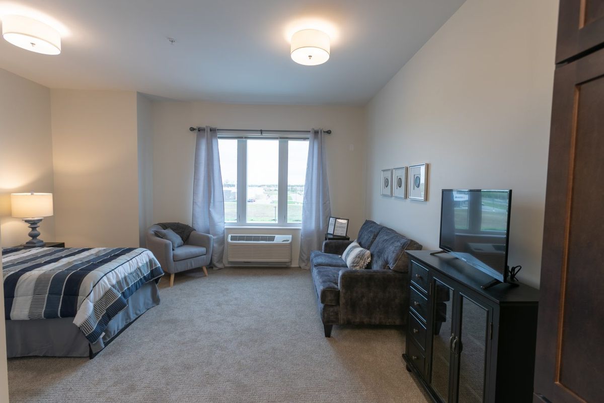 A cozy living space featuring a sofa, bed, and large window with natural light.