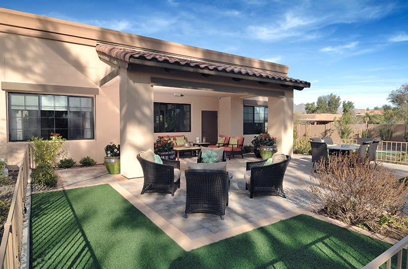 A cozy outdoor patio with seating arrangement in a backyard setting.