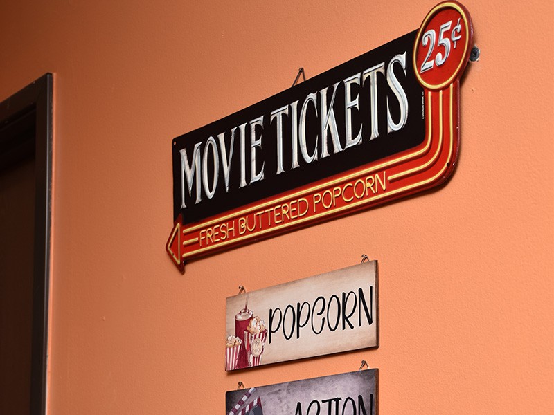Vintage movie theater sign advertising tickets for 25 cents and popcorn.