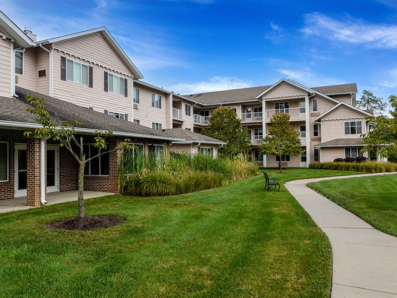 A peaceful apartment complex surrounded by greenery and a clear blue sky.