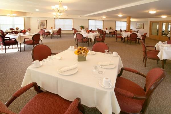 An elegantly set dining area with round tables and red chairs.