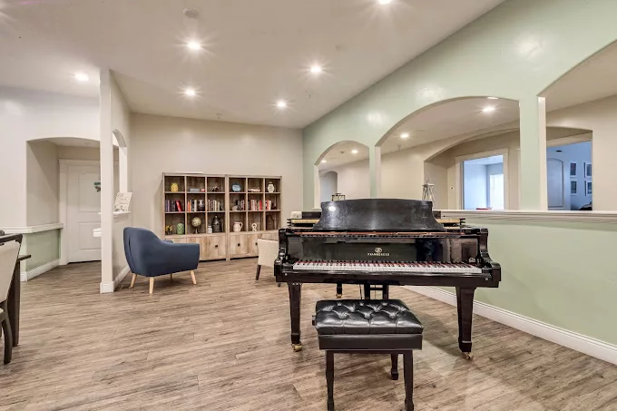 A stylish living room featuring a grand piano, bookshelf, and modern furnishings.