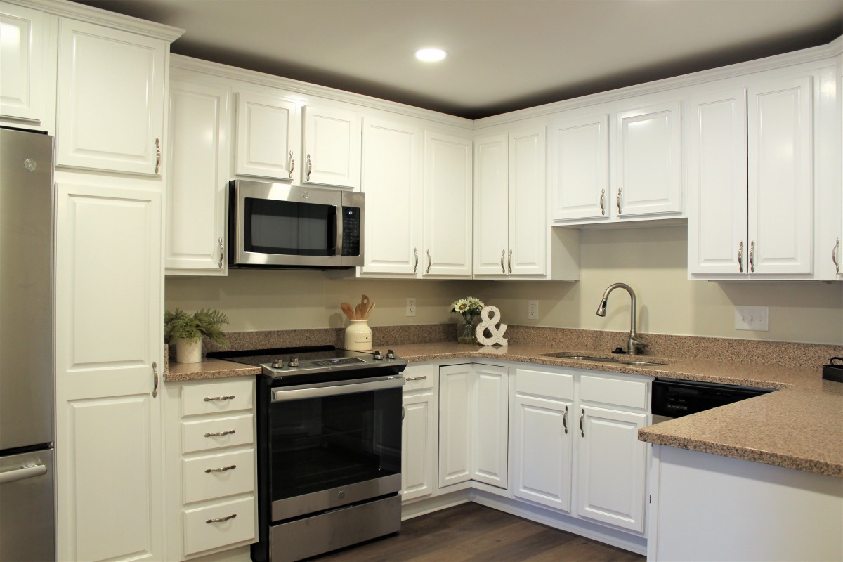 Modern kitchen with white cabinets and stainless steel appliances.